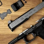Glock 19 Gen 6 pistol field-stripped on a wood surface, with slide, frame, MOS adapter plate, red dot optic, mounting screws, and hex wrench laid out. Slide is stamped "Glock 19 Gen 6 / 9x19 / Austria.