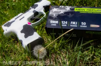 New Republic 9mm Luger 124 Grain FMJ Training Ammunition 50-Round box beside a cow-print pistol resting on grass